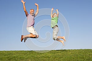 Senior man with grandson jumping in air