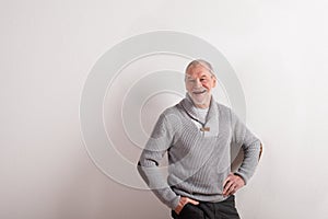 Senior man in gray woolen sweater, studio shot.