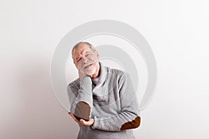 Senior man in gray woolen sweater, studio shot.