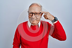 Senior man with grey hair standing over isolated background smiling pointing to head with one finger, great idea or thought, good