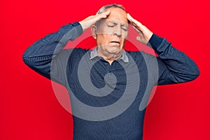 Senior man with grey hair wearing casual polo with hand on head, headache because stress