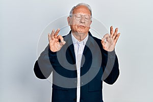 Senior man with grey hair wearing casual style and glasses relax and smiling with eyes closed doing meditation gesture with