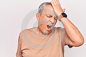 Senior man with grey hair wearing casual t-shirt surprised with hand on head for mistake, remember error