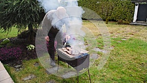 Senior Man grilling the meat on charcoal grill.