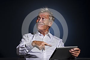 Senior man grinning and pointing to his tablet