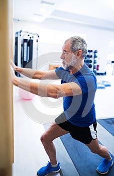 Senior man in gym working out, stretching his legs