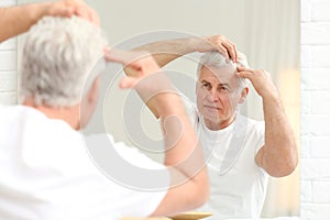 Senior man with hair loss problem looking in mirror