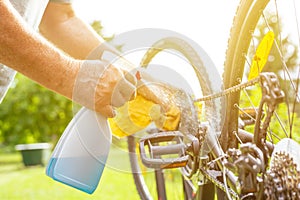 Senior man hand cleaning the bike by spray and rag, doing maintenance of his bicycle, sport concept