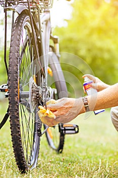 Senior man hand cleaning the bike by spray and rag, doing maintenance of his bicycle, sport concept