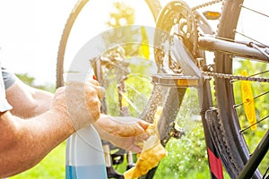 Senior man hand cleaning the bike by spray and a rag, doing maintenance of his bicycle, sport concept