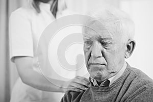 Senior man with hand of supporting nurse on his shoulder