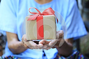 Senior man hands holding gift box with red ribbon for Christmas