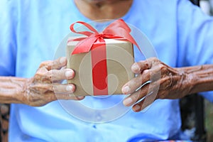 Senior man hands holding gift box with red ribbon for Christmas