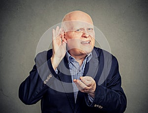 Senior man, hard of hearing, placing hand on ear asking someone to speak up