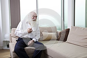 Senior man having coffee while sitting on sofa in apartment