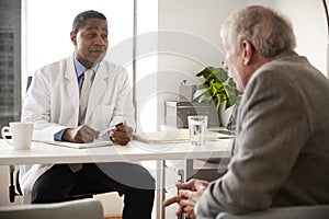 Senior Man Having Consultation With Male Doctor In Hospital Office