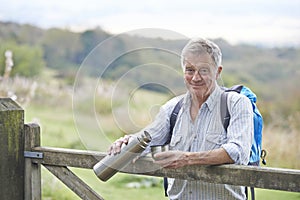 Senior Man Having Drink From Flask Whilst On Walk