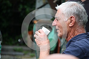 A senior man having a drink from plastic glass