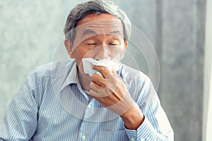 Senior man having sickness and sneezing into tissue, Healthcare photo