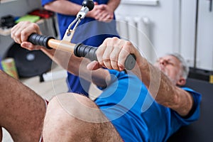 Senior man having trx lesson and working out with his coach in gym