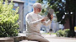 Senior man having video call on tablet pc in city