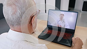 Senior man having videoconferencing with online male doctor. Remote patient consulting video call in conference virtual