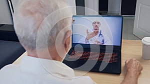 Senior man having videoconferencing with online male doctor. Remote patient consulting video call in conference virtual