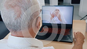 Senior man having videoconferencing with online male doctor. Remote patient consulting video call in conference virtual