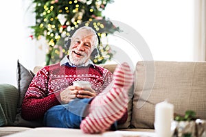 A senior man with headphones listening to music at home at Christmas time.