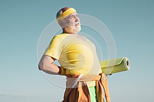 Senior man in health club. Elderly man practicing sports on blue sky background. Portrait of healthy senior sport man