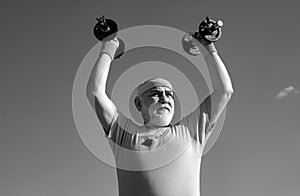 Senior man in health club. Old mature man exercising with dumbbell. Portrait of senior man holding dumbbell. Senior male