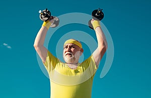 Senior man in health club. Old mature man exercising with dumbbell. Portrait of senior man holding dumbbell. Senior male