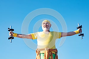 Senior man in health club. Senior fitness man training with dumbbells isolated on blue background. Senior sportman