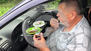 Senior man healthy eating while sitting inside of passenger car on driver seat