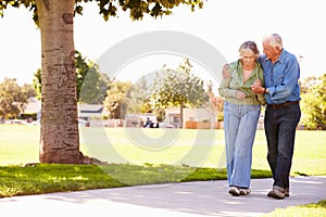 Senior Man Helping Wife As They Walk In Park Together