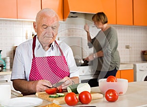 Senior man helping wife to cook