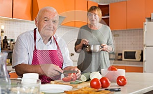 Senior man helping wife to cook