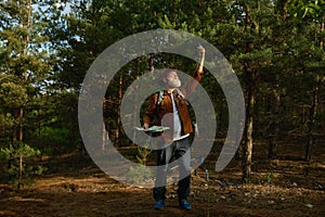 Senior man hiker comparing rout on paper map and navigation app on phone