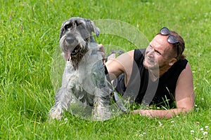 Senior man and his dog lying on the grass in the park.