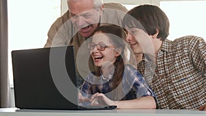 Senior man and his grandchildren entertain on laptop