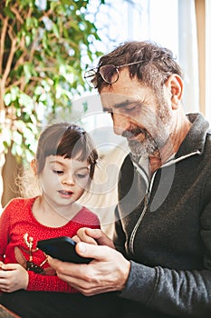 Senior man and his granddaughter using smartphone