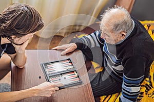 Senior man and his grandson play backgammon