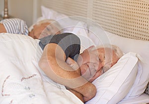 Senior man and his wife asleep in bed at home