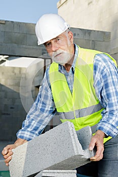 senior man holding bloc cement outdoors photo