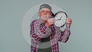 Senior man holding clock watch, hiding, checking time on clock, running late to work being in delay