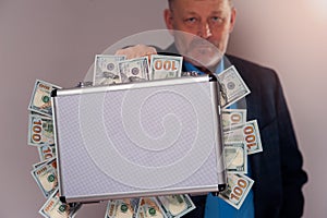 Senior man holding metal briefcase with dollars