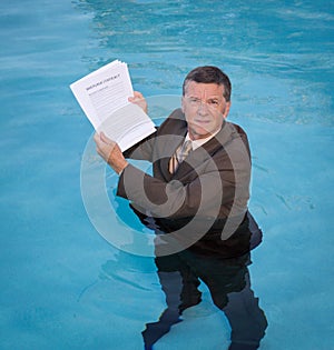 Senior man holding mortgage loan document in water