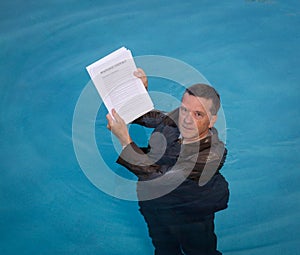 Senior man holding mortgage loan document in water