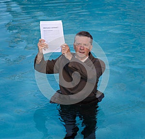 Senior man holding mortgage loan document in water