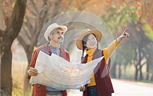 senior man holding paper map talking with young adult daughter while she is pointing index to the location direction